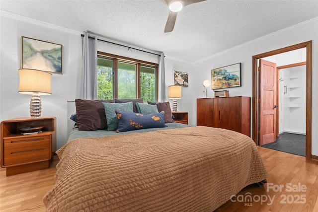 bedroom with crown molding, a textured ceiling, a ceiling fan, and wood finished floors