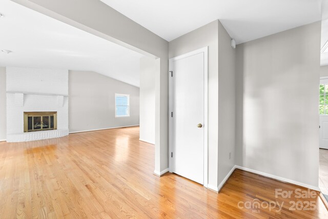 unfurnished living room with plenty of natural light, lofted ceiling, and light wood-style floors