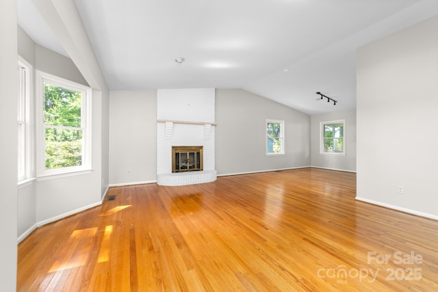 unfurnished living room with plenty of natural light, light wood finished floors, visible vents, and lofted ceiling