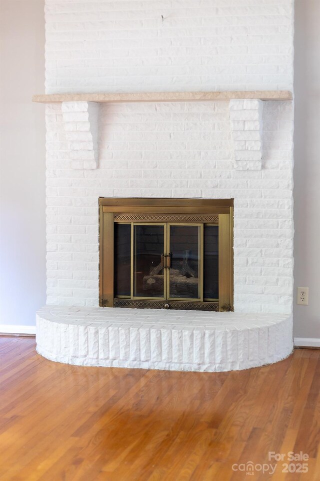 room details with baseboards, wood finished floors, and a fireplace