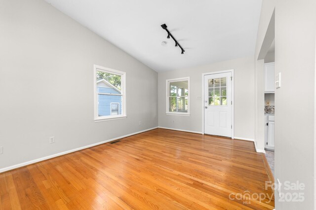 interior space with baseboards, plenty of natural light, light wood finished floors, and rail lighting