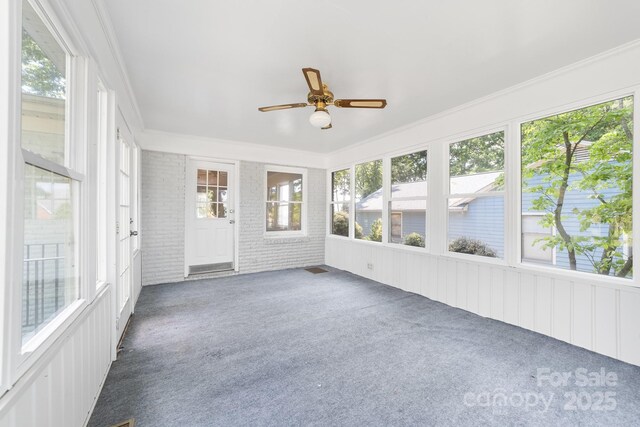 unfurnished sunroom featuring a ceiling fan and a wealth of natural light