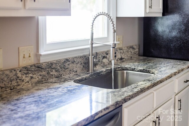 details with a sink, white cabinetry, and light stone countertops
