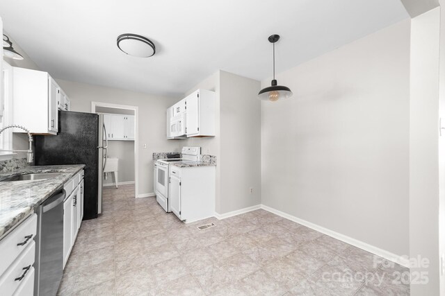 kitchen with light stone countertops, a sink, baseboards, white cabinets, and white appliances