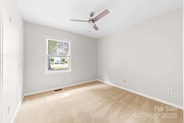carpeted spare room with a ceiling fan, baseboards, and visible vents