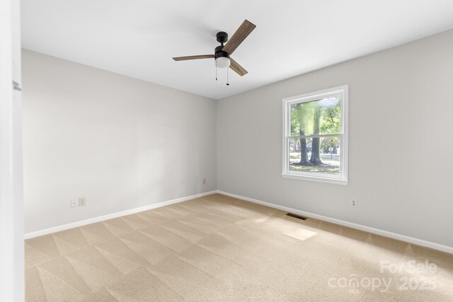 empty room with baseboards, light carpet, and visible vents