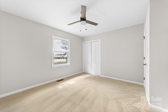 unfurnished bedroom with light colored carpet, baseboards, visible vents, and a closet