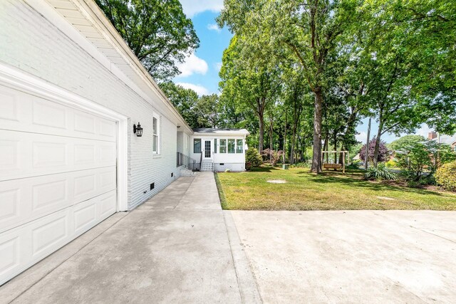 view of yard featuring entry steps, an attached garage, and driveway