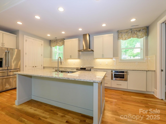 7324 Leharne Dr, Charlotte, NC 28270 - kitchen featuring appliances with stainless steel finishes, a sink, white cabinets, wall chimney exhaust hood, and an island with sink