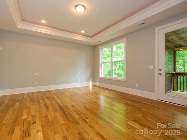 7324 Leharne Dr, Charlotte, NC 28270 - spare room with visible vents, crown molding, baseboards, light wood finished floors, and a tray ceiling