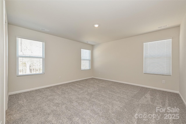 empty room featuring carpet flooring, baseboards, and visible vents