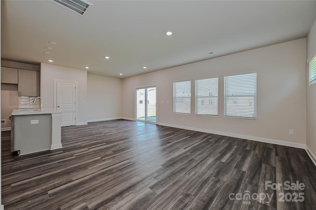 unfurnished living room featuring recessed lighting, baseboards, dark wood finished floors, and visible vents