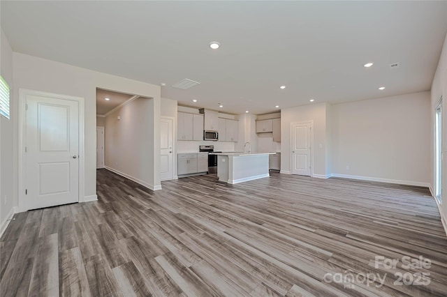 unfurnished living room featuring light wood-type flooring, recessed lighting, baseboards, and visible vents