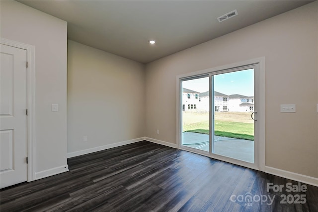 spare room featuring dark wood-style flooring, baseboards, visible vents, and recessed lighting