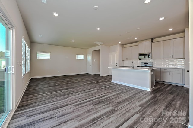 kitchen featuring decorative backsplash, dark wood-style flooring, open floor plan, stainless steel appliances, and recessed lighting