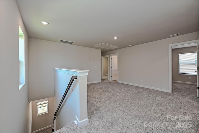 unfurnished room featuring visible vents, attic access, carpet flooring, and a wealth of natural light