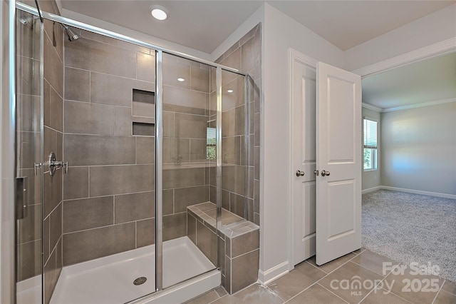 full bath featuring crown molding, baseboards, tile patterned flooring, and a stall shower