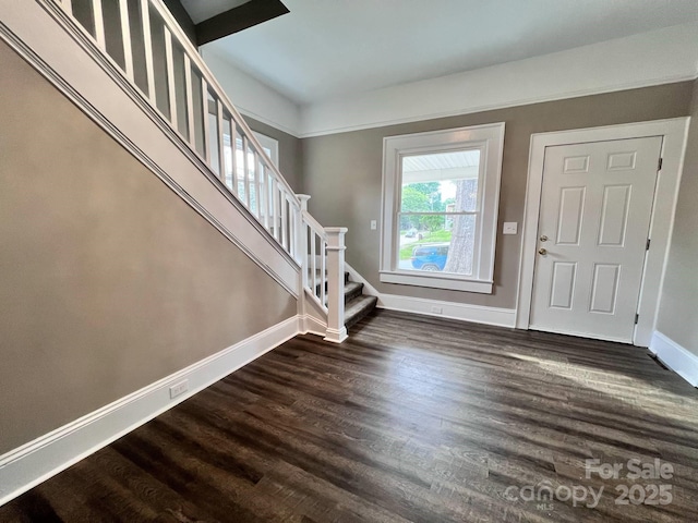 foyer entrance featuring baseboards, stairs, and dark wood finished floors