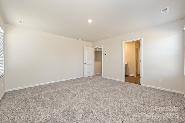 unfurnished bedroom with carpet floors, baseboards, visible vents, and ensuite bathroom