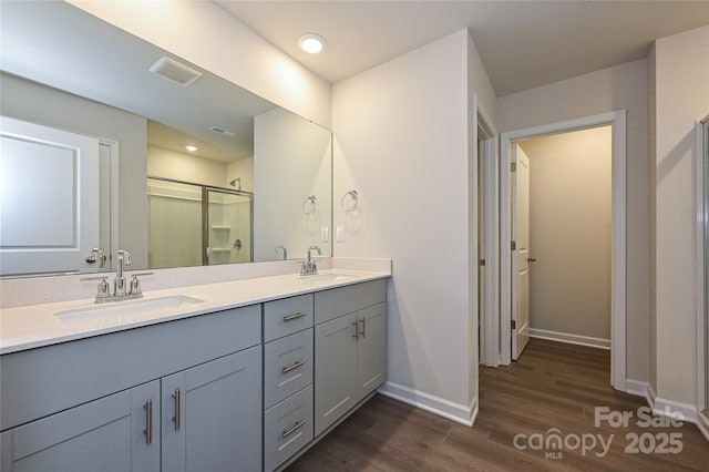 bathroom featuring a sink, baseboards, a shower stall, and wood finished floors