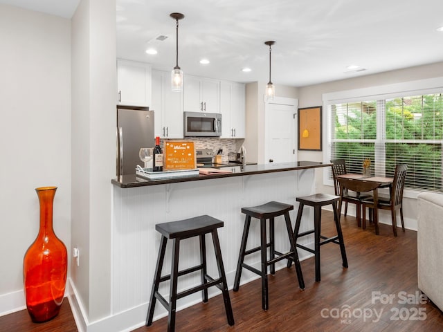 12 Martin Valley Rd, Swannanoa, NC 28778 - kitchen with appliances with stainless steel finishes, dark countertops, dark wood finished floors, tasteful backsplash, and white cabinetry