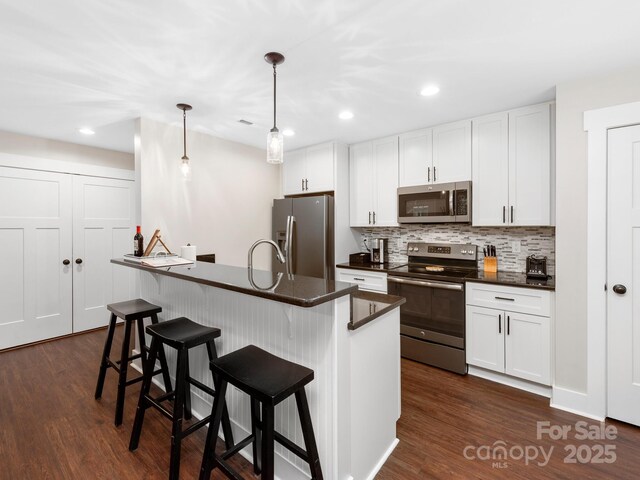 12 Martin Valley Rd, Swannanoa, NC 28778 - kitchen featuring stainless steel appliances, dark countertops, a breakfast bar area, backsplash, and dark wood-type flooring
