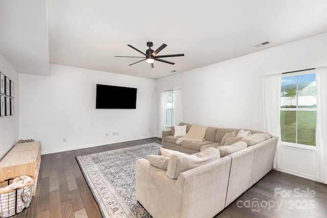 living room with plenty of natural light, a ceiling fan, visible vents, and dark wood finished floors