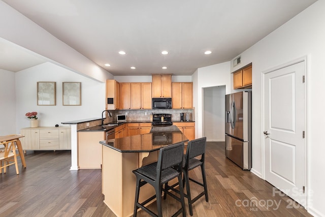 kitchen with a sink, black appliances, visible vents, dark wood-style flooring, and backsplash