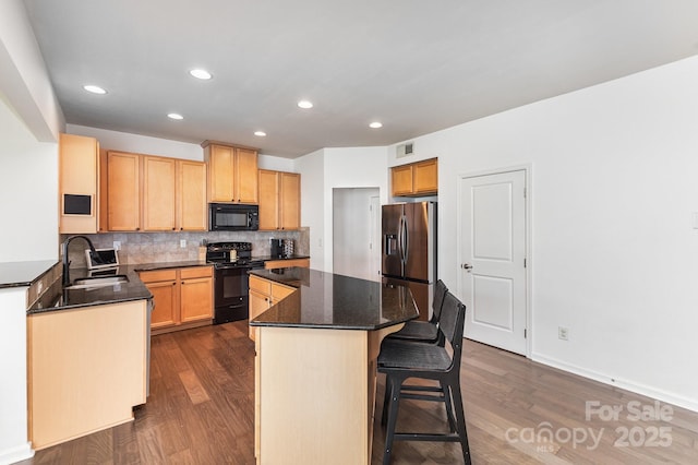 kitchen with dark wood-style flooring, black appliances, a sink, and a kitchen island