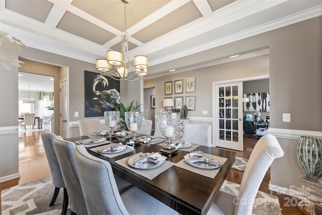 dining room with wood finished floors, a chandelier, crown molding, coffered ceiling, and beam ceiling