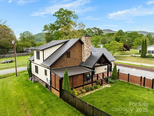 back of property with a chimney, metal roof, a standing seam roof, a mountain view, and central AC unit