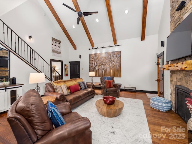 living room with high vaulted ceiling, beam ceiling, a ceiling fan, wood finished floors, and a fireplace
