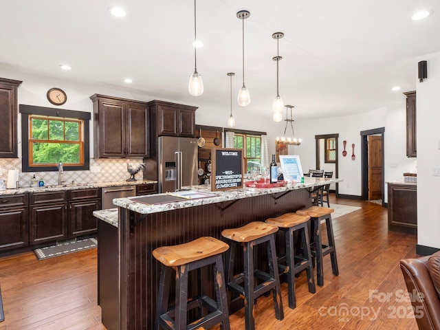kitchen featuring stainless steel appliances, a sink, dark brown cabinets, tasteful backsplash, and dark wood-style floors