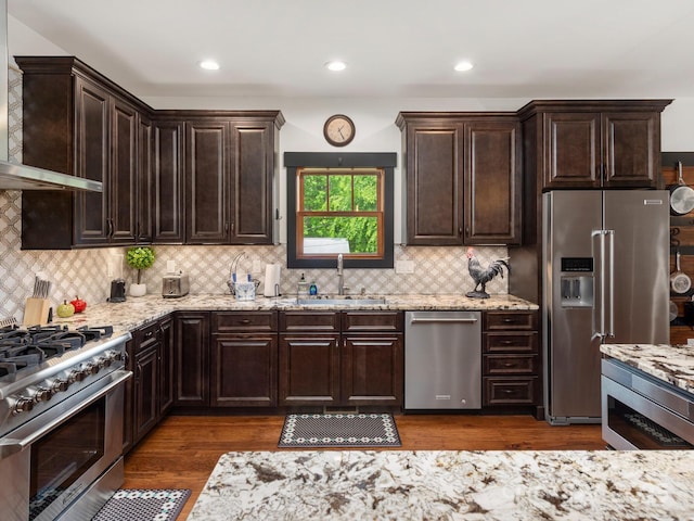 kitchen with high end appliances, a sink, custom range hood, light stone countertops, and recessed lighting