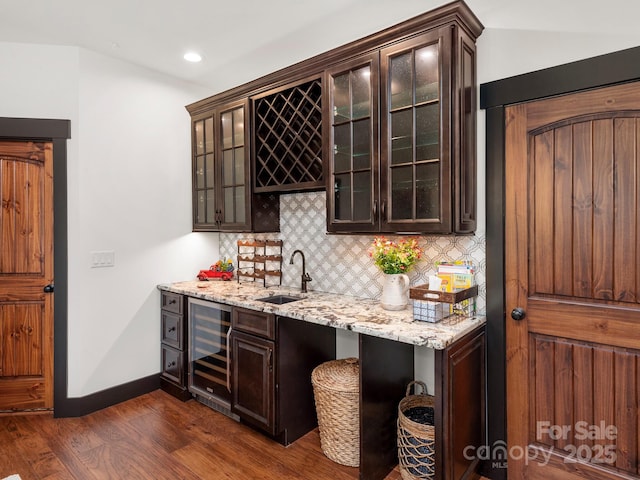 indoor wet bar with beverage cooler, dark wood-type flooring, backsplash, recessed lighting, and baseboards