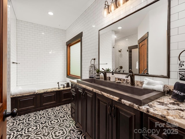 full bath featuring a tile shower, tile walls, a bath, vanity, and recessed lighting