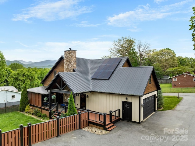 view of front facade featuring a chimney, a porch, solar panels, metal roof, and a mountain view