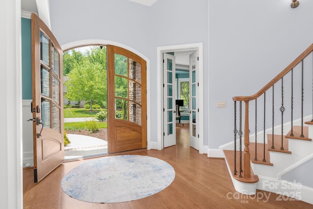 entrance foyer featuring french doors, baseboards, stairs, and wood finished floors