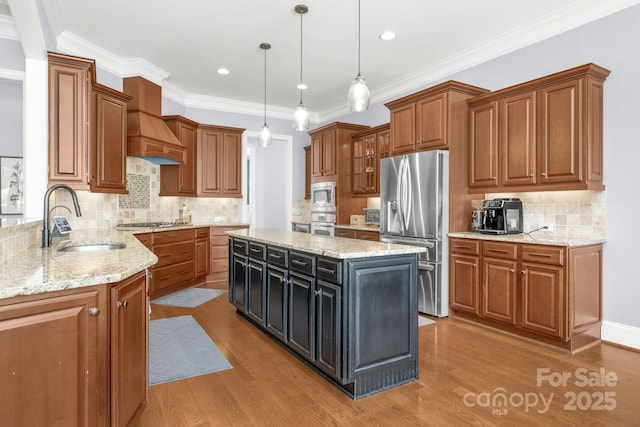 kitchen featuring brown cabinetry, a sink, light wood finished floors, and stainless steel appliances