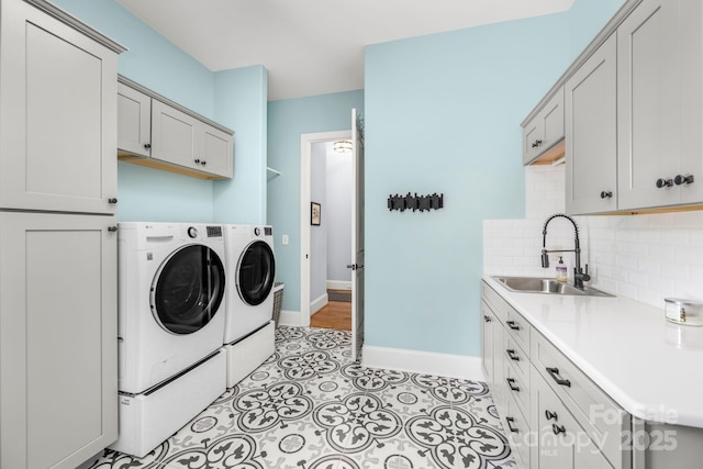 washroom featuring a sink, separate washer and dryer, baseboards, and cabinet space