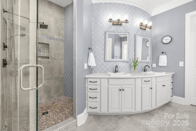 full bathroom with a sink, ornamental molding, a shower stall, and double vanity