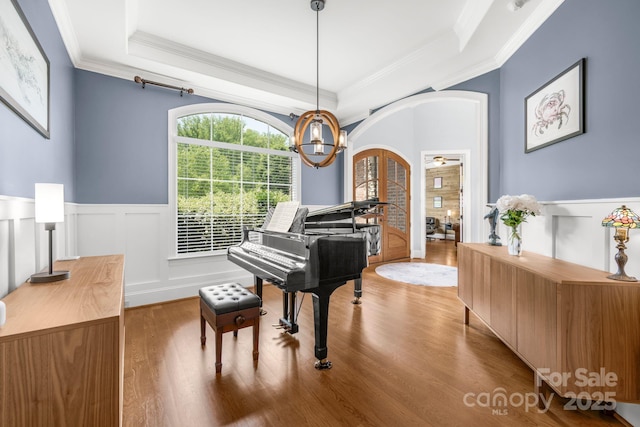 sitting room featuring ornamental molding, wainscoting, wood finished floors, a raised ceiling, and french doors
