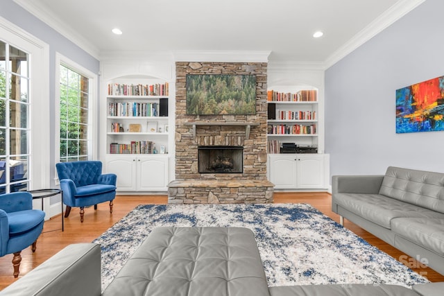 living room with crown molding, built in features, a stone fireplace, and wood finished floors