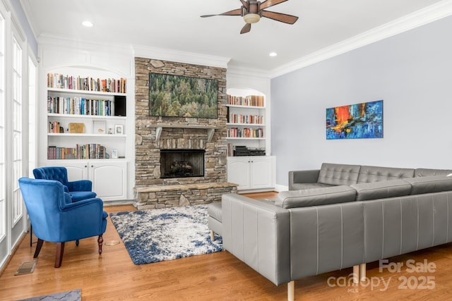 living area with ceiling fan, visible vents, crown molding, a fireplace, and wood finished floors