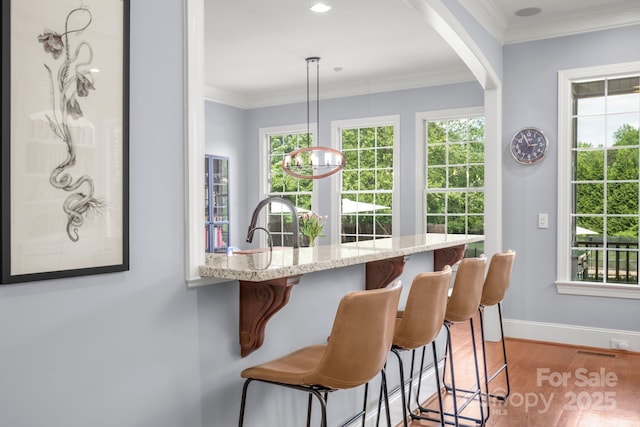 bar with visible vents, wood finished floors, baseboards, a chandelier, and ornamental molding