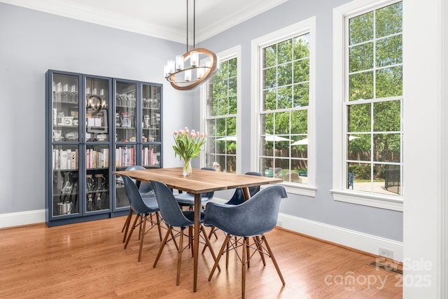 dining area with baseboards, an inviting chandelier, ornamental molding, and wood finished floors