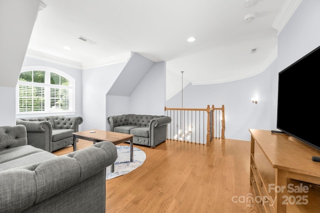 living area with visible vents, ornamental molding, and light wood-style floors