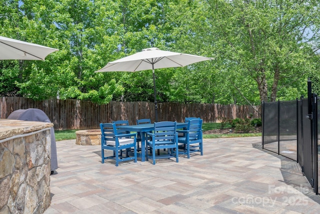 view of patio / terrace with outdoor dining area, a fire pit, and a fenced backyard
