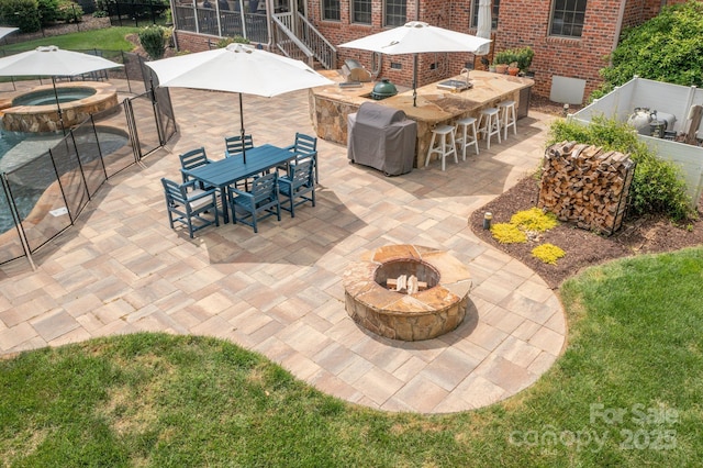 view of patio with fence, outdoor dry bar, an in ground hot tub, and a fire pit