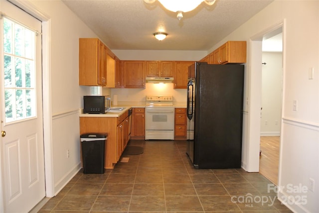 177 Line Dr, Forest City, NC 28043 - kitchen with dark tile patterned floors, light countertops, freestanding refrigerator, white electric range oven, and under cabinet range hood